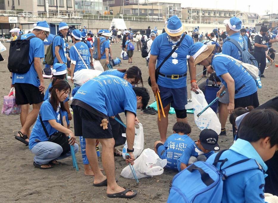 片瀬東浜海水浴場で青色のサンタ姿で清掃活動をするイベントの参加者＝15日午後、神奈川県藤沢市