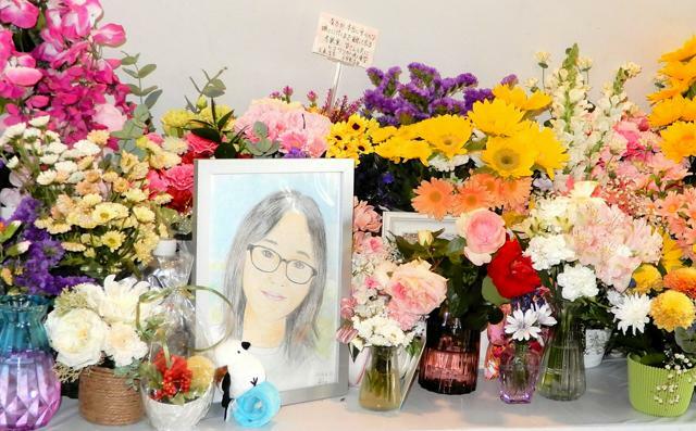 似顔絵を囲むように花などで埋め尽くされた献花台=2024年6月30日、北海道旭川市の中央公園