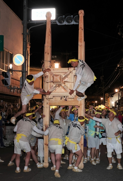 威勢のいい掛け声とともに、みこしを転がす担ぎ手たち＝23日午後9時12分、木曽町福島