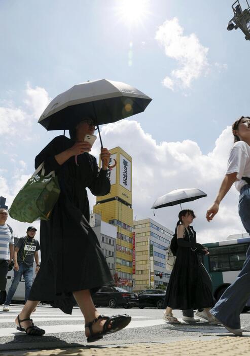 強い日差しの中、日傘を差して歩く人たち。気象庁は山口県を含む九州北部が梅雨明けしたとみられると発表した＝22日午前、福岡市