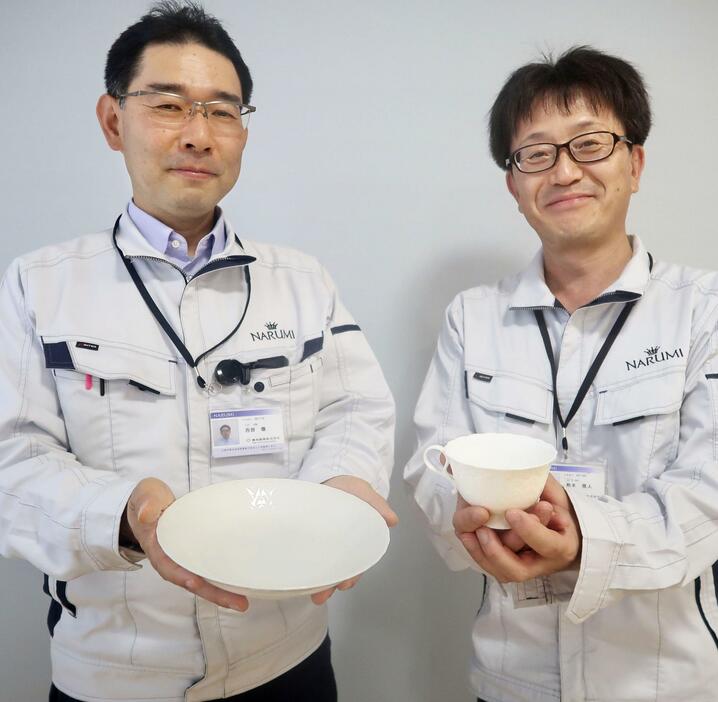 廃棄される卵の殻を使った高級食器「ボーンチャイナ」を手にする鳴海製陶研究開発部の西部徹部長（左）ら＝5月、名古屋市