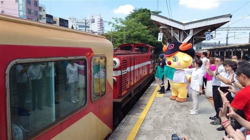 出発する一番列車に手を振って送り出す阿里山林業鉄路のマスコットキャラクター「鉄鹿站長（駅長）」ら。中国語では「鉄鹿」の発音が「鉄路（鉄道）」と同じ＝2024年7月6日、嘉義駅