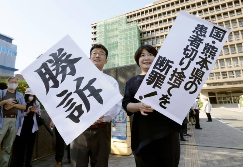 水俣病特別措置法に基づく救済策で対象外となった人たちが国などに損害賠償を求めた訴訟の判決で、「勝訴」などと書かれた紙を掲げる原告側の弁護士ら＝２０２３年９月２７日、大阪地裁前