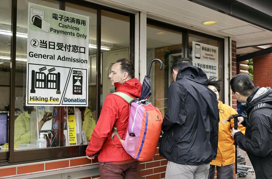 山開きを迎えた富士山の山梨県側で、通行料を支払う登山者たち＝1日午前