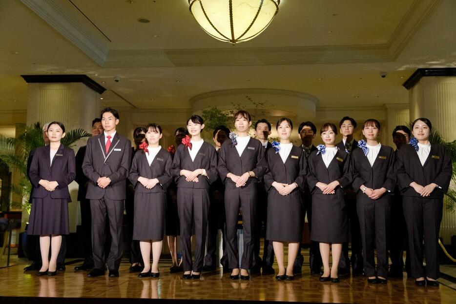 ユニホーム委員会メンバーの加藤優羽さん（左）と新ユニホームを着用する「JR東海ホテルズ」6ホテルのホテルスタッフ。小物のデザインでホテルごとの特徴を表現
