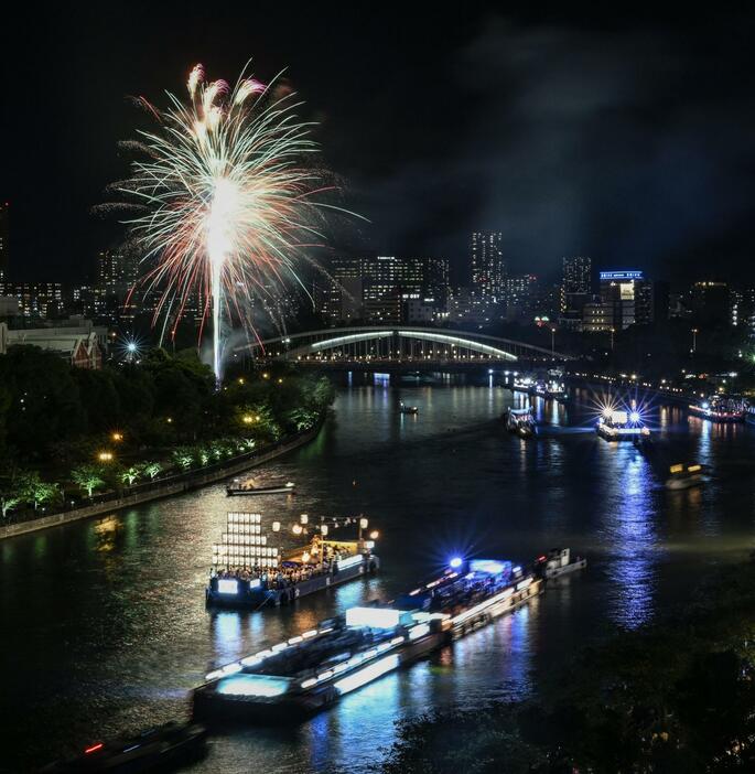 奉納花火が夜空を彩り、最高潮を迎えた天神祭の「船渡御」＝25日夜、大阪市