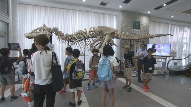 恐竜の骨のレプリカを見学する小学生