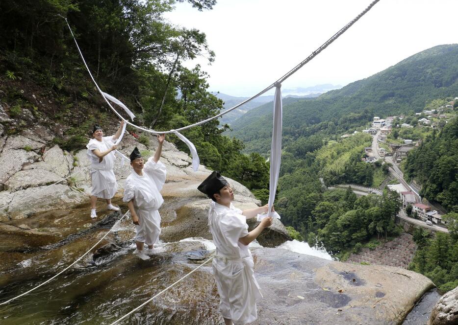 「那智の滝」の上に架かるしめ縄を張り替える熊野那智大社の神職＝9日午前、和歌山県那智勝浦町