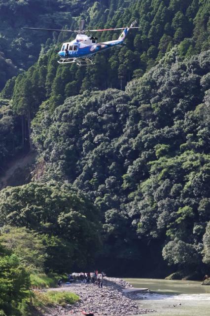 綾北川で不明となった男性を捜索する県防災救急ヘリや消防、警察関係者＝２３日午後３時５６分、綾町北俣