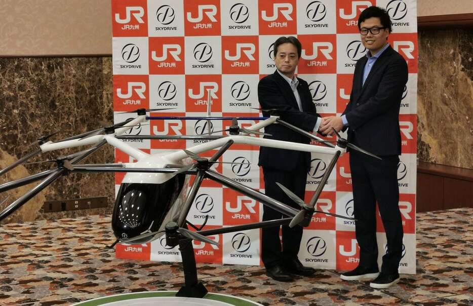 空飛ぶクルマの模型を前にするスカイドライブの福沢知浩ＣＥＯ（右）＝４日、東京都