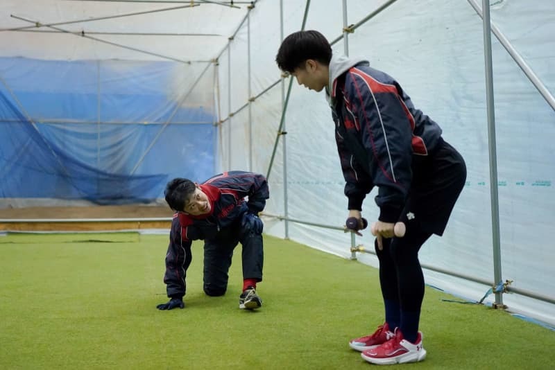 体育館内に作ったブルペンでウオーミングアップする稲毛さん（左）ら＝３月、山形県中山町