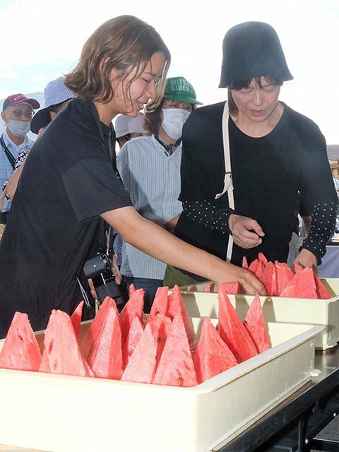 振る舞われたスイカを試食する来場者