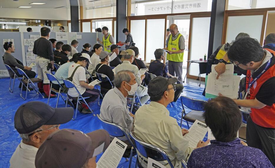 活動開始前に注意事項など説明を受けるボランティア＝30日午前、山形県酒田市