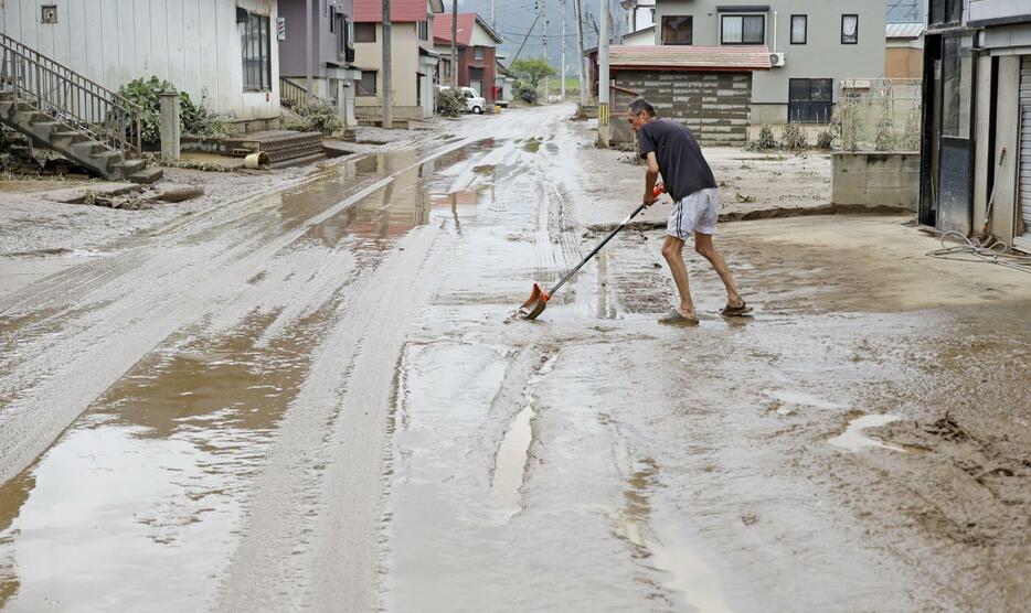 山形県戸沢村の蔵岡地区で泥をかき出す長沢修さん＝28日午前11時2分