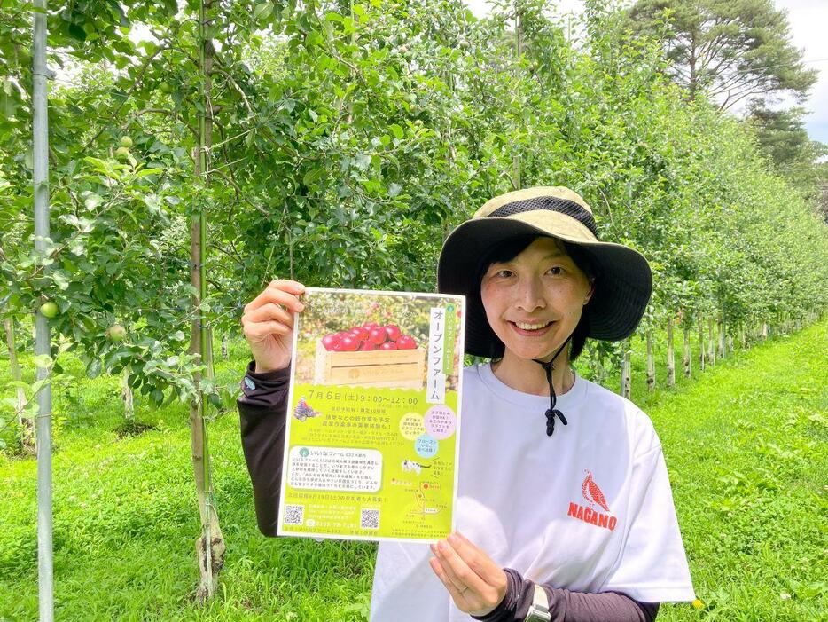 リンゴ果樹園の前でチラシを持つ吉崎諒子さん