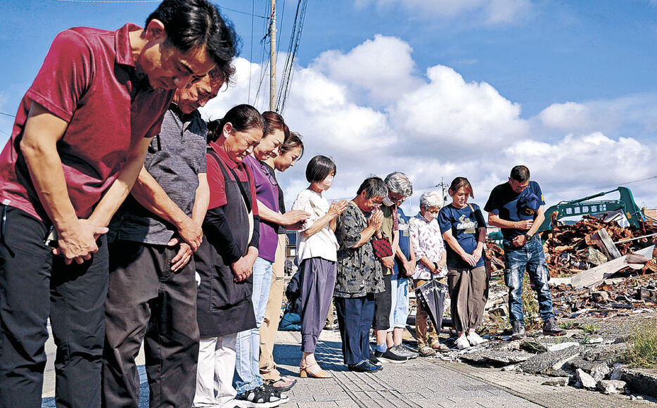 大規模火災があった朝市通り周辺で黙とうをささげる輪島朝市の組合員＝１日午後４時１０分、輪島市河井町