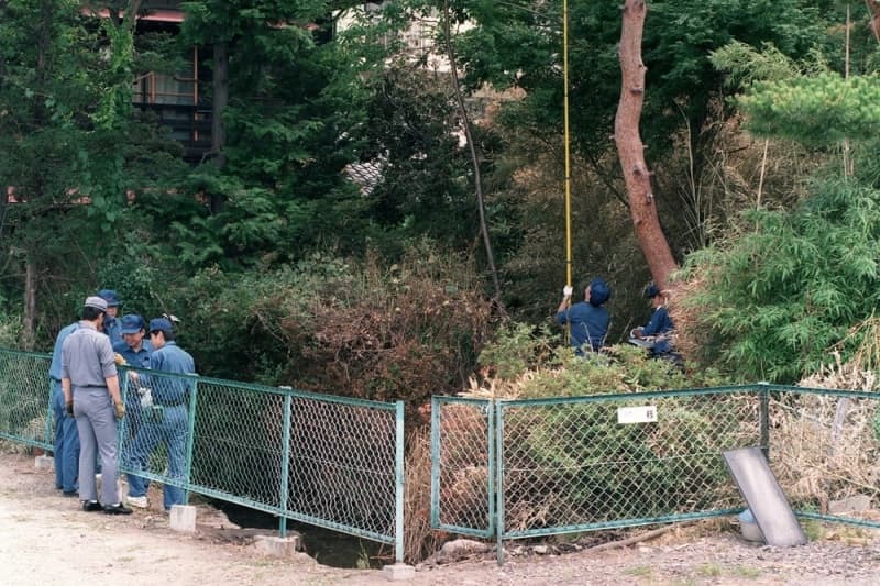 １９９４年７月、松本サリン事件で、サリンが検出された池付近を検証する長野県警の捜査員＝長野県松本市