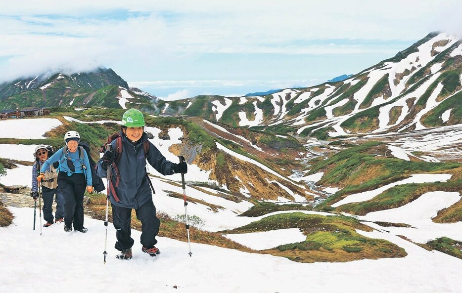 雪が残る景色を楽しみながら歩みを進める登山者＝立山・室堂平