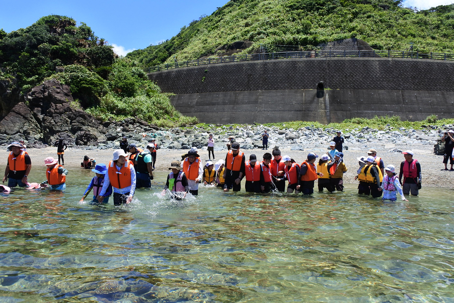 海面をたたきながら魚を追い込む児童生徒と保護者＝6日、鹿児島県奄美市名瀬（提供写真）