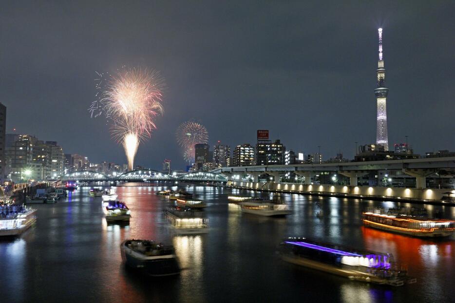 東京・隅田川花火大会で打ち上げられた花火。右は東京スカイツリー＝27日夜（多重露光）