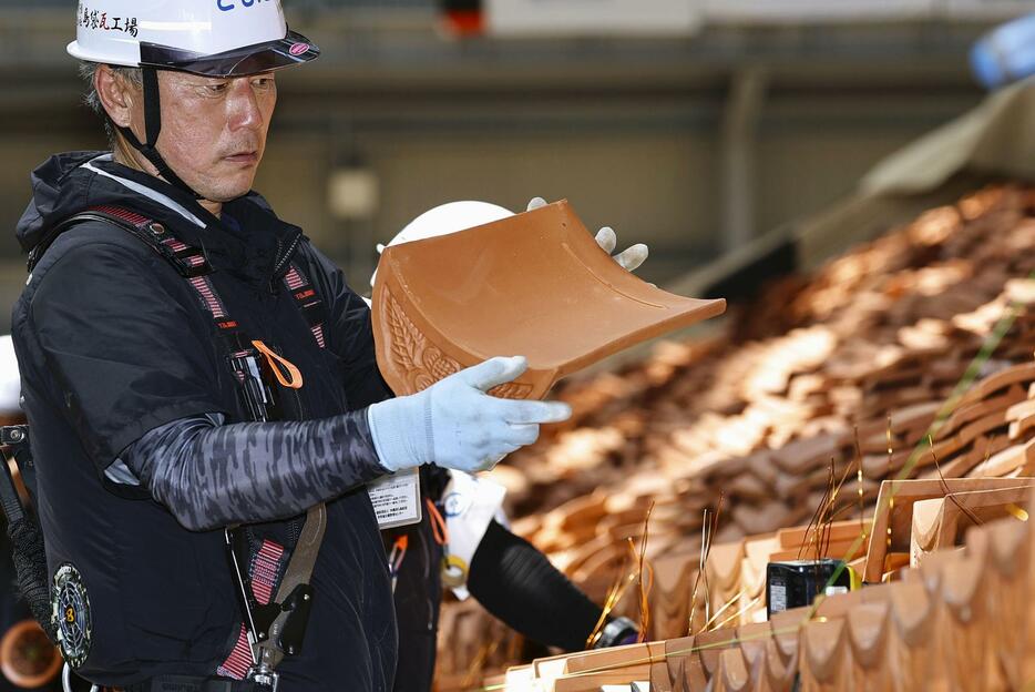 再建中の首里城正殿で、赤瓦で屋根をふく作業を行う職人＝15日午後、那覇市