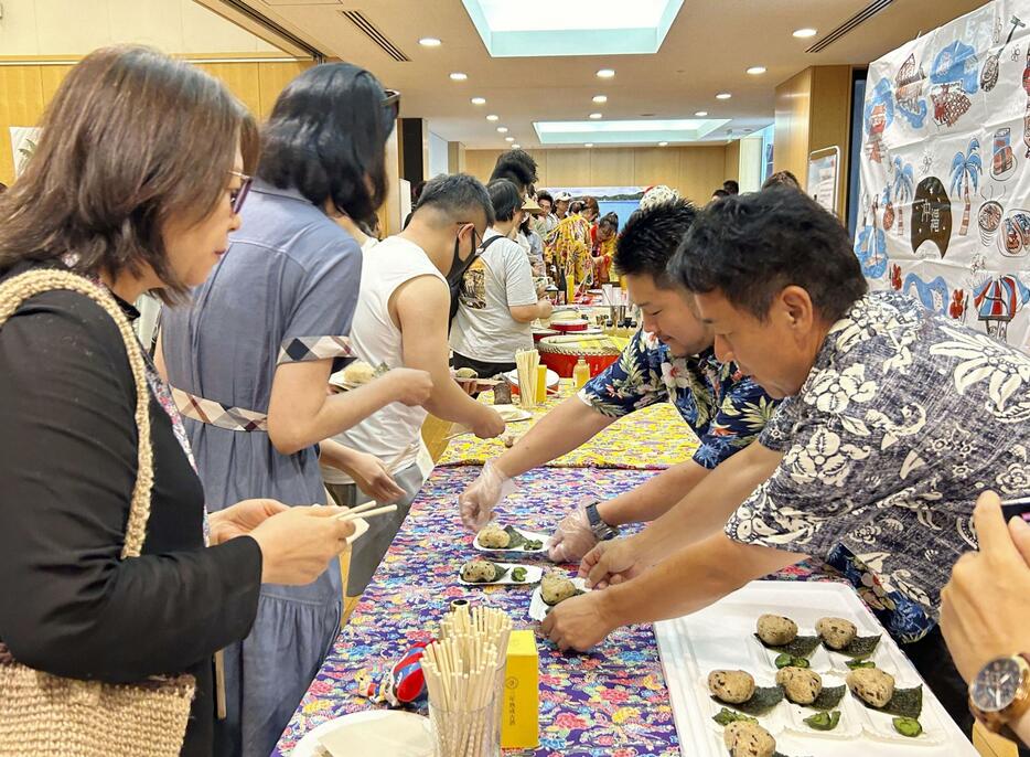 沖縄PRイベントで沖縄料理を試食する中国人参加者（左）＝17日、北京の日本大使館（共同）