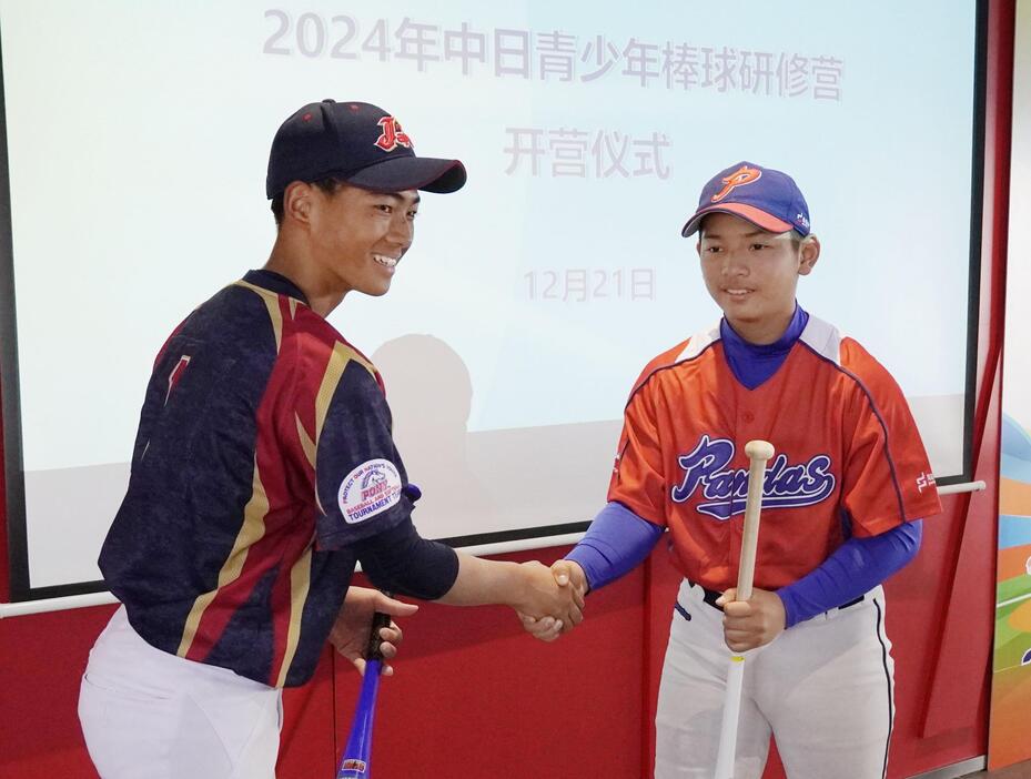 少年野球チームの交流式典で握手を交わす日本の選手（左）と中国の選手＝21日、中国広東省中山市（共同）