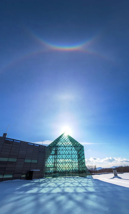 ガラスのピラミッドの頂上と重なる太陽の上空に現れた、上から「環天頂アーク」「ラテラルアーク」「タンジェントアーク」=30日午後1時、札幌市東区のモエレ沼公園（北波智史撮影）