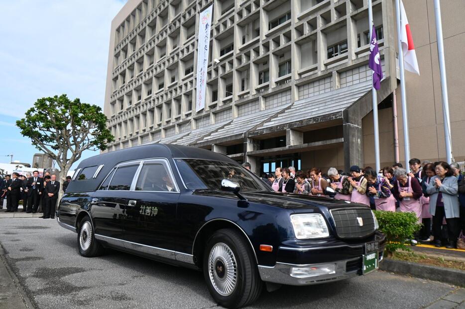 桑江朝千夫沖縄市長を乗せた霊きゅう車を見送る市職員ら＝13日、沖縄市役所