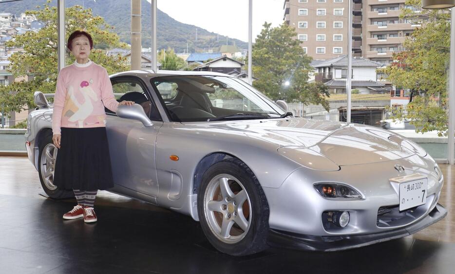 製造元マツダへの譲渡を前に、愛車「RX-7」の横に立つ西本尚子さん＝18日午後、長崎市