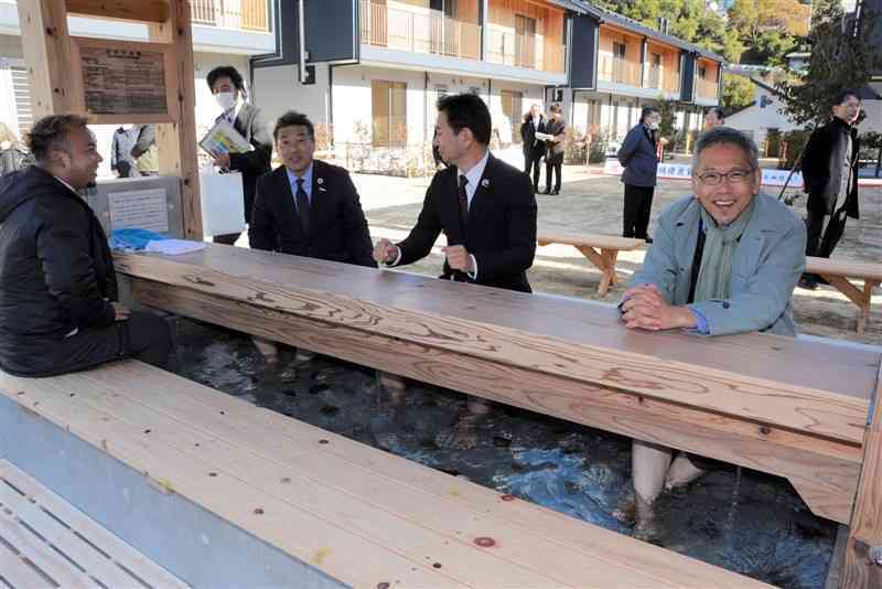 「友田団地」に設けられた足湯で温まる落成式出席者ら＝19日、芦北町