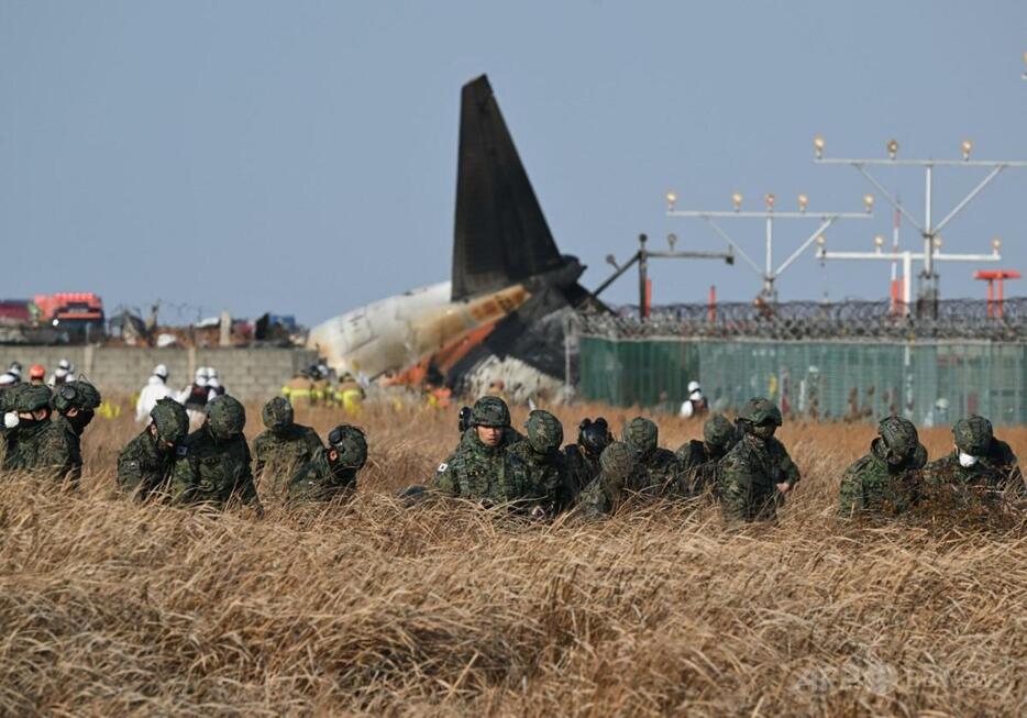 韓国南西部の務安国際空港で、着陸に失敗した済州航空の旅客機の残骸付近で行方不明者を捜索する兵士（2024年12月29日撮影）。【翻訳編集】 AFPBB News