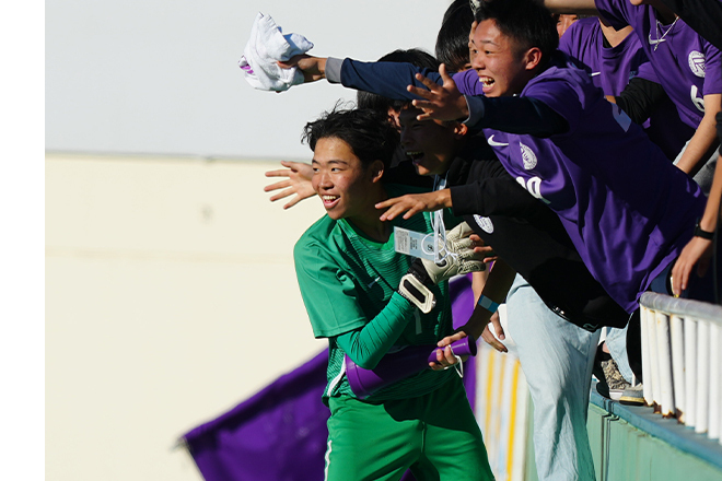 那覇西戦の勝利に貢献したGK吉田。応援席にいた部員と喜びを分かち合う。写真：早草紀子