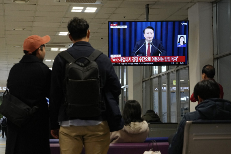 韓国の尹錫悦大統領の緊急談話について伝えるテレビニュースを見る人々＝ソウルで2024年12月3日、AP