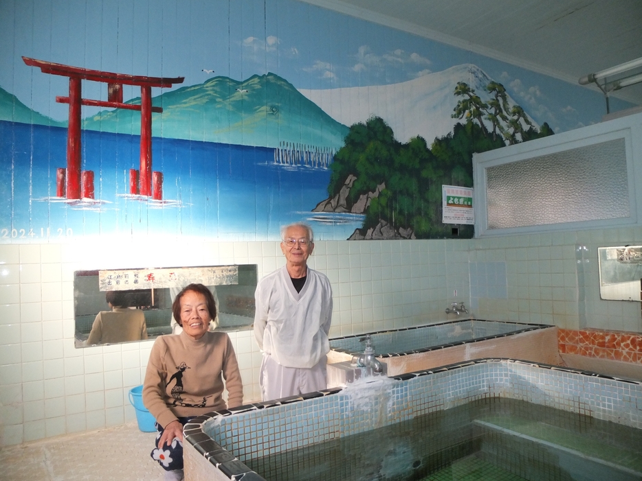 復活したペンキ絵に笑顔を見せる青山さん夫妻＝湖西市新居町の「みどり湯」で