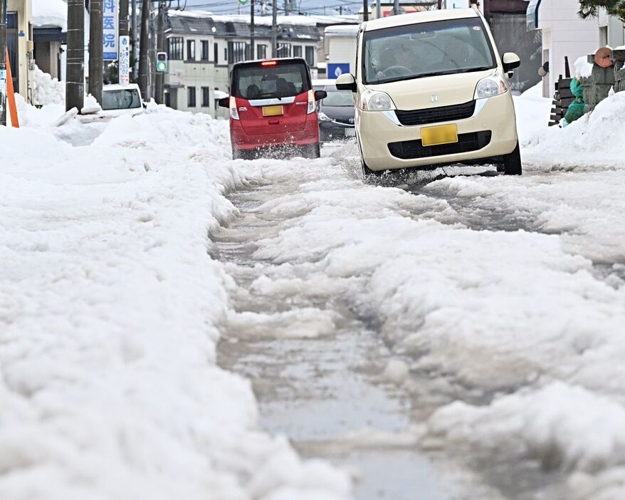 雨の影響で、雪の多い道路はわだちに段差ができた＝26日午前、青森市青葉2丁目