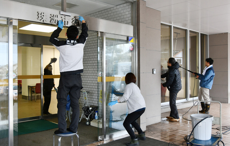 元日に起きた能登半島地震の被災地では２７日、市役所などで仕事納めとなった。写真は、珠洲市役所の正面玄関を掃除する市職員ら＝同日午後