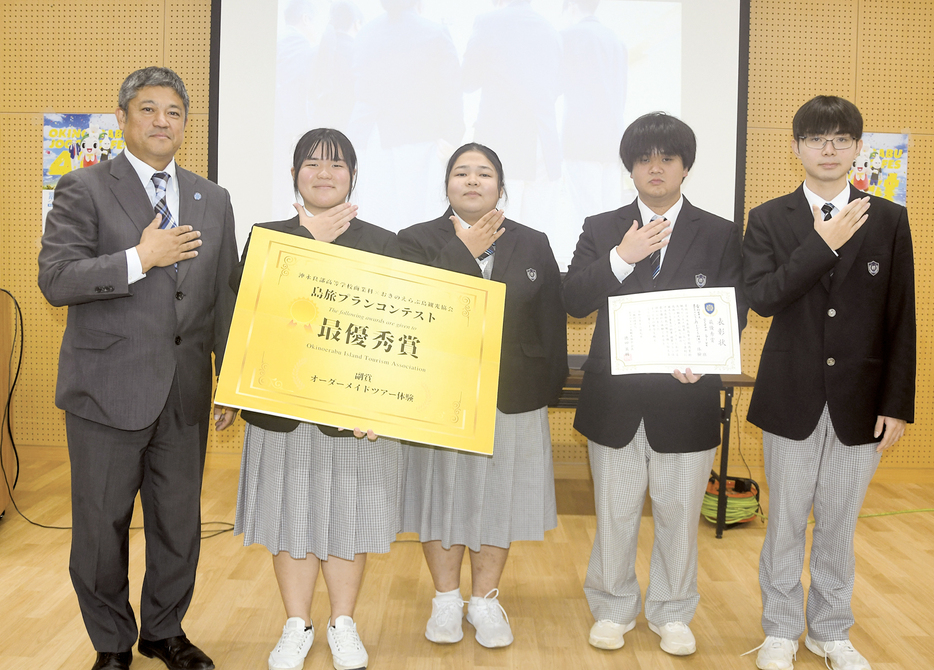 最優秀賞に選ばれ、德田英輔おきのえらぶ島観光協会長（左）から表彰を受けたocean　blue班の生徒＝9日、鹿児島県沖永良部島