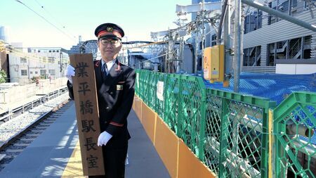 とうきょうスカイツリー駅下り線ホームで旧駅名時代の「業平橋駅長室」の看板を持つ荒木健二駅長。上り線ホームはひと足先に東側（画面奥）に移転している（記者撮影）