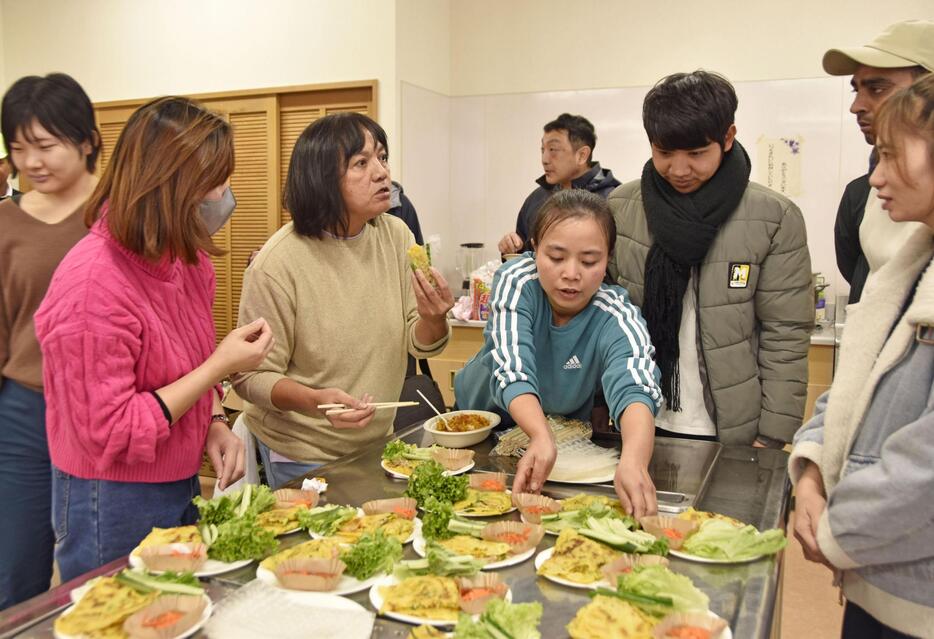 石川県輪島市で市内在住の外国人の交流会が開かれ、手作りの母国料理を振る舞う参加者ら＝22日午後