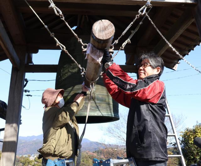 城山の鐘の撞木を雑巾で磨く鐘守の日高康彦（右）、真理子さん夫婦＝２７日午前、延岡市・城山公園