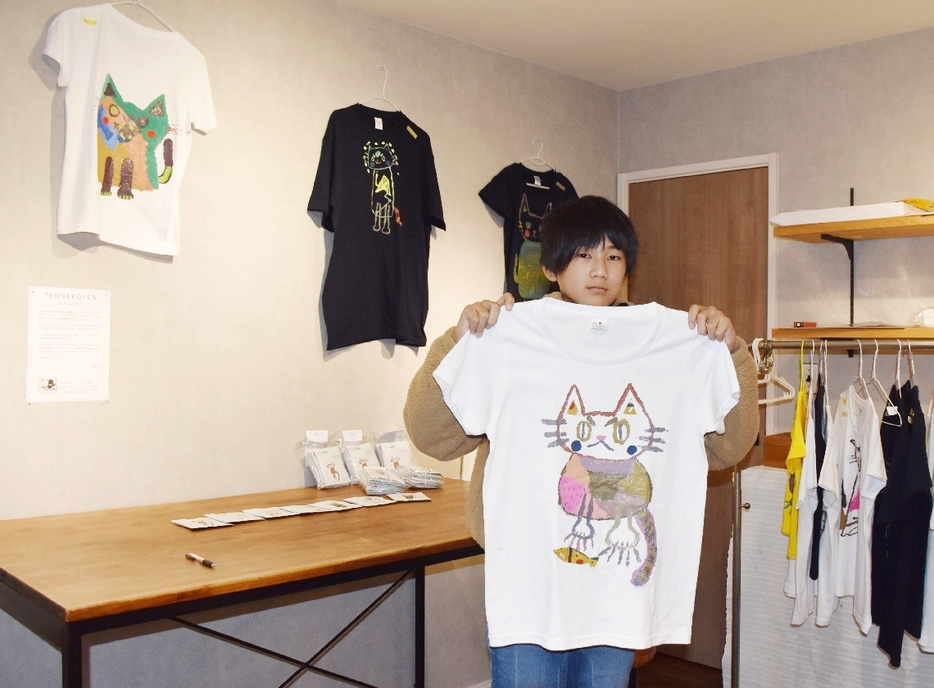 自作のネコのTシャツを手にする藤井天真さん＝由布市挾間町古野