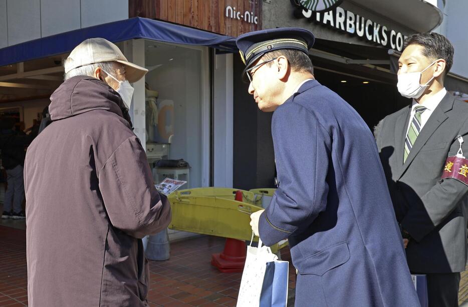 チラシを配る警視庁成城署の須山浩道署長（中央）＝14日午前、東京都世田谷区成城