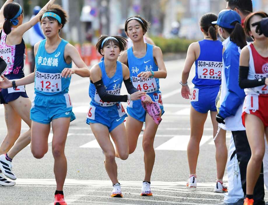 神村学園の１区野口（右）が小倉にたすきを渡す＝京都市