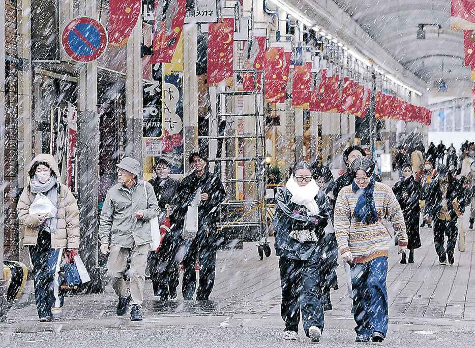 降りしきる雪の中を歩く買い物客ら＝２２日午後１時、富山市総曲輪