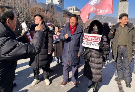 　１２月１６日、    韓国の尹錫悦大統領が「非常戒厳」の宣言を正当化する理由として、選挙へのハッキングと「反国家」的な北朝鮮シンパの存在を挙げた時、右派の人気ユーチューバー、コ・ソングク氏には聞き覚えがあった。写真は１４日、ソウルで開かれた尹大統領支持者の集会で、ファンと撮影に応じるコ氏（２０２４年　ロイター/Ju-min Park）