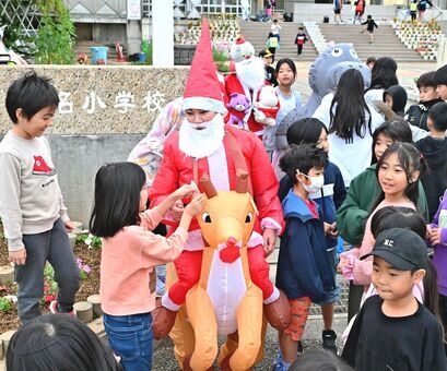 サンタやカバなどに仮装した保護者らを囲む児童ら＝２５日、那覇市・識名小学校（金城拓撮影）