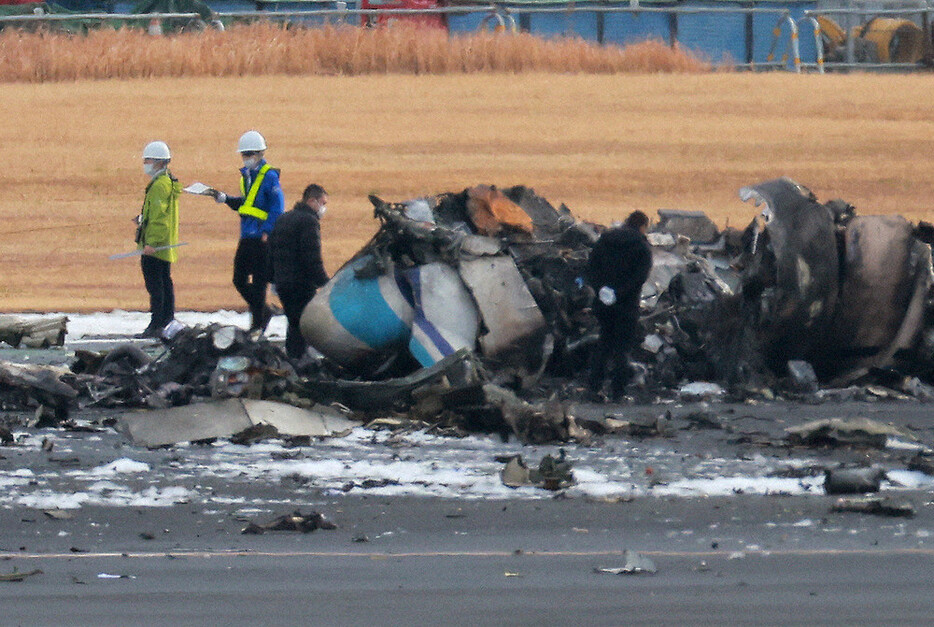 日航機と衝突して炎上した海上保安庁の航空機周辺を調べる関係者ら＝羽田空港で３日午前９時４２分、渡部直樹撮影