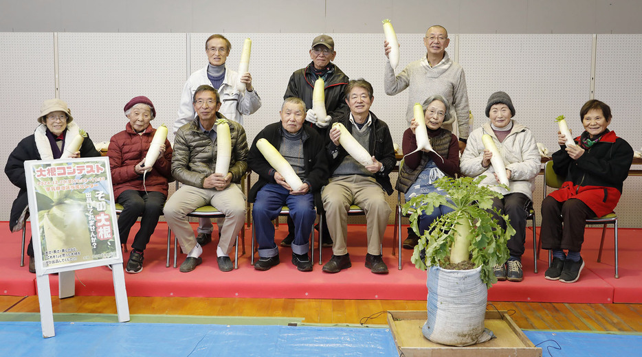 自慢の大根を掲げる出品者の皆さん＝柚原町の宇気郷地区市民センターで