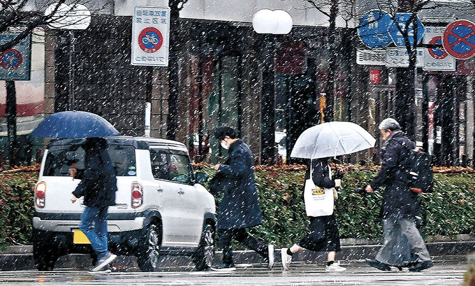 雪が降る中、先を急ぐ人＝１８日午前９時１０分、富山駅前